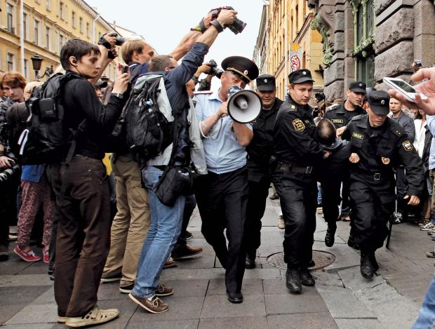 Photographers take pictures of riot police detaining a man during a protest in St. Petersburg, against a court verdict in Kirov sentencing Russian opposition leader Alexei Navalny to five years in jail, July 18, 2013