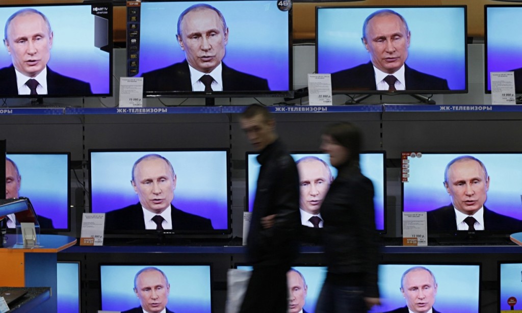 Покупатели в центральной части города Красноярска проходят мимо экранов, показывающих трансляцию Владимира Путина. Фото: Илья Наймушин / ИЛЬЯ Наймушин / Reuters / Corbis