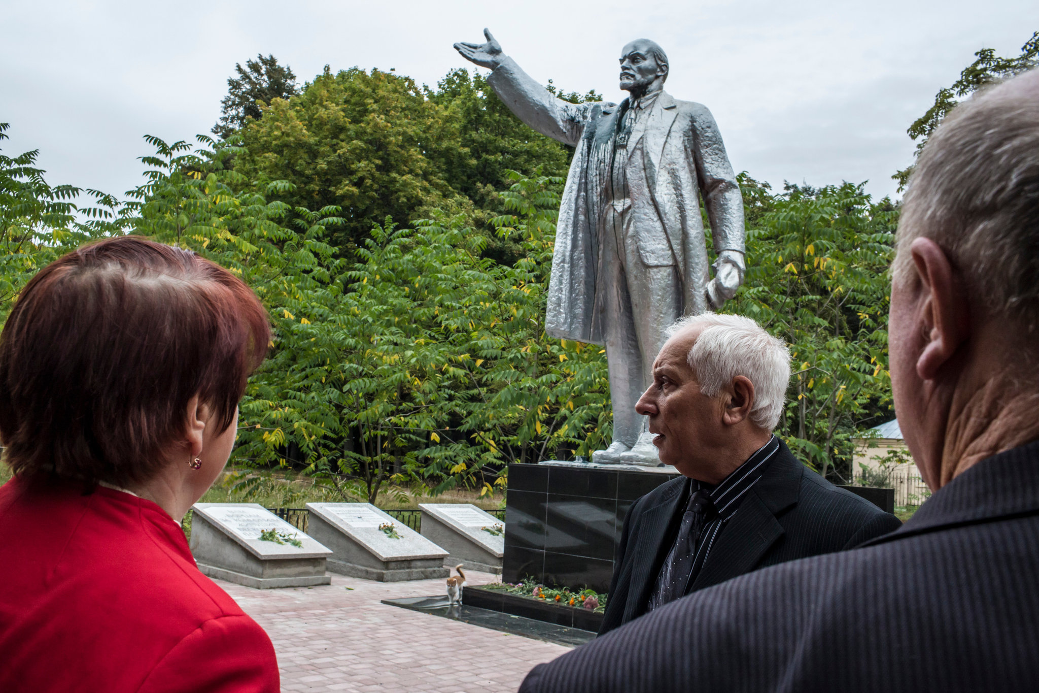 Ivan Papchenko, center, and the Lenin statue moved from town square to a remote spot in a park in Semyonovka, Ukraine. Credit Brendan Hoffman for The New York Times