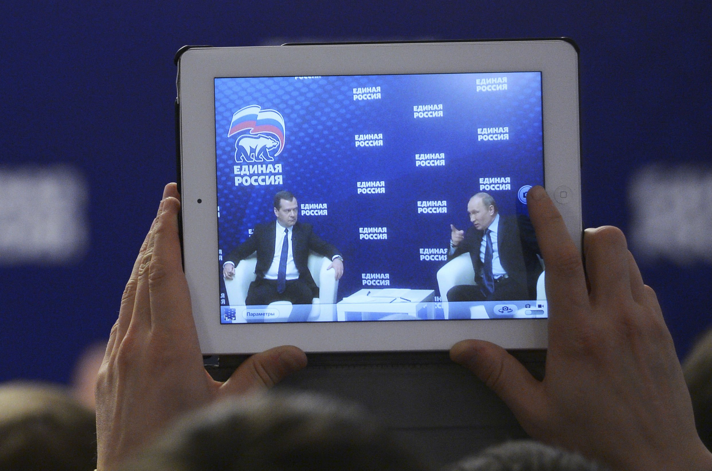Russia's President Vladimir Putin (R) and Prime Minister Dmitry Medvedev are seen on a screen of a tablet computer during a meeting with members and activists of the United Russia political party in Moscow region, October 3, 2013. Credit: REUTERS/Alexander Astafyev/RIA Novosti/Pool 