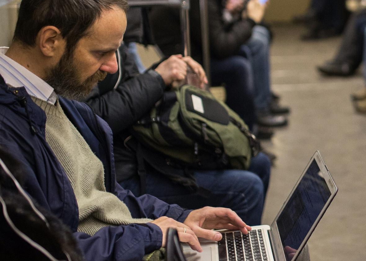 A commuter consult his laptop inside a train coach in the Moscow Metro, on Dec. 1, 2014. Photo by DMITRY SEREBRYAKOV/AFP/Getty Images