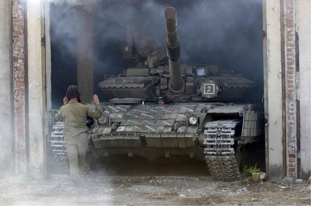 Член на военните сили на самообявената Луганска народна република помага на танк да се паркира след изтеглянето му от фронтовата линия до Луганск . REUTERS/Alexander Ermochenko (Atlantic Council)